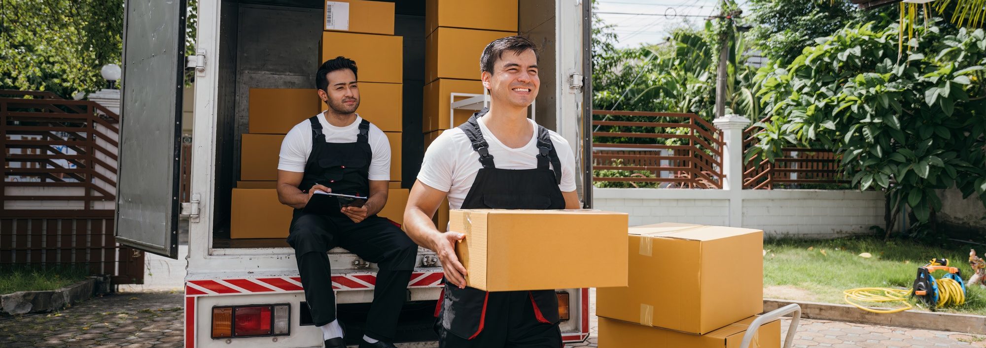 Moving service workers unload boxes from a van showing teamwork and cooperation. Delivery men in